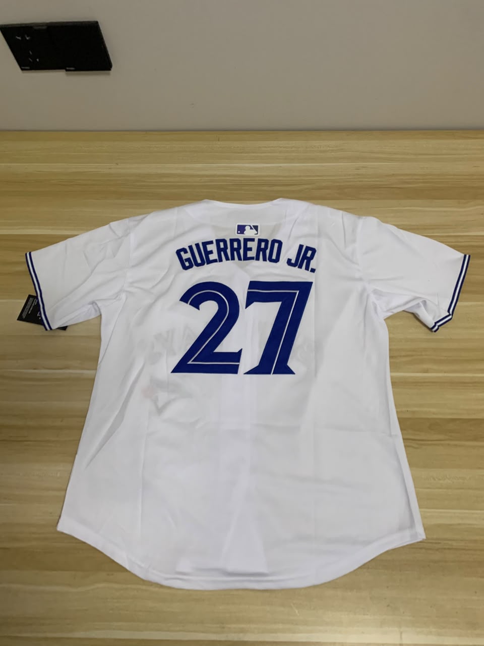 White baseball jersey with blue lettering and number on a wooden surface